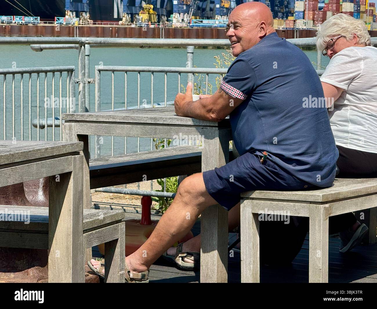 Felixstowe, Suffolk - 16. Juni 2025 : heißer Sommernachmittag. Mann mittleren Alters mit Glatze und Sonnenbräune. Auf dem Deck des Viewpoint Cafés. Stockfoto