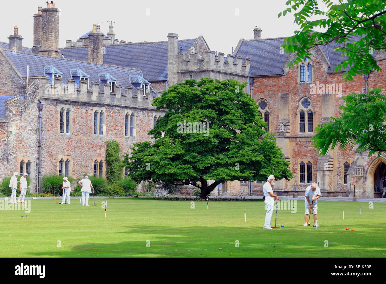 Mitglieder des Palace Croquet Club spielen ein Spiel auf dem Rasen des Bishop's Palace, Wells, Somerset, England, Großbritannien. Juni 2025. Sommer Stockfoto