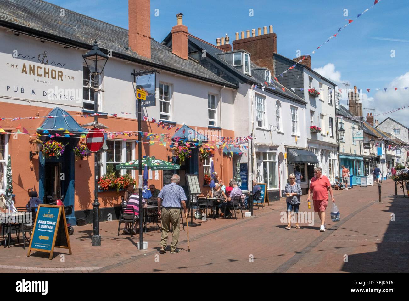 Sidmouth, Devon. Die Menschen genießen das herrliche Wetter im Juni auf der Old Fore Street in Sidmouth. Stockfoto
