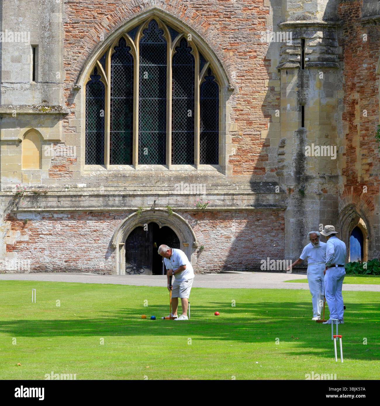 Mitglieder des Palace Croquet Club spielen ein Spiel auf dem Rasen des Bishop's Palace, Wells, Somerset, England, Großbritannien. Juni 2025. Sommer Stockfoto