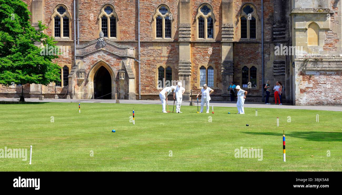 Mitglieder des Palace Croquet Club spielen ein Spiel auf dem Rasen des Bishop's Palace, Wells, Somerset, England, Großbritannien. Juni 2025. Sommer Stockfoto