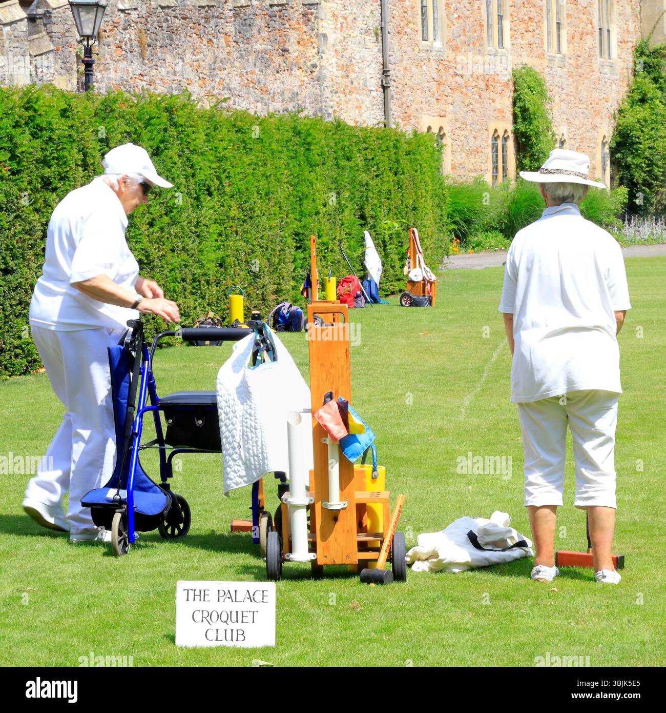 Mitglieder des Palace Croquet Club spielen ein Spiel auf dem Rasen des Bishop's Palace, Wells, Somerset, England, Großbritannien. Juni 2025. Sommer Stockfoto