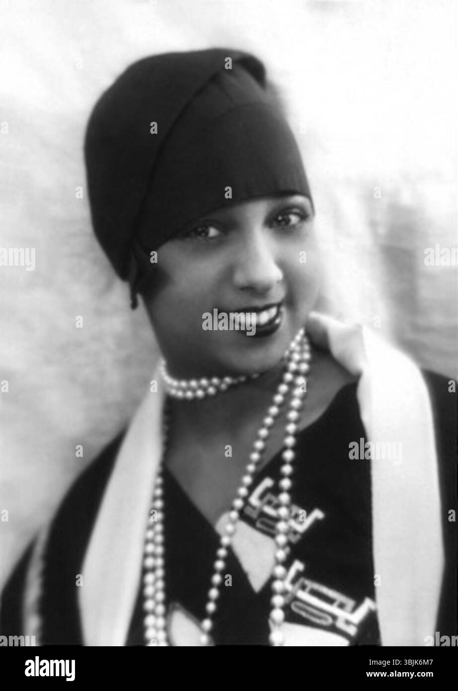 Dieses Foto von Joséphine Baker aus dem Jahr 1930, aufgenommen von Paul Nadar, fängt die berühmte Tänzerin und Sängerin in einem ruhigen Moment ein und zeigt ihre Eleganz und ihr unverwechselbares Charisma. Baker war für ihre Auftritte in Paris in den 1920er Jahren bekannt, wo sie zu einer einflussreichen Persönlichkeit in der Unterhaltung und Kultur wurde. Stockfoto
