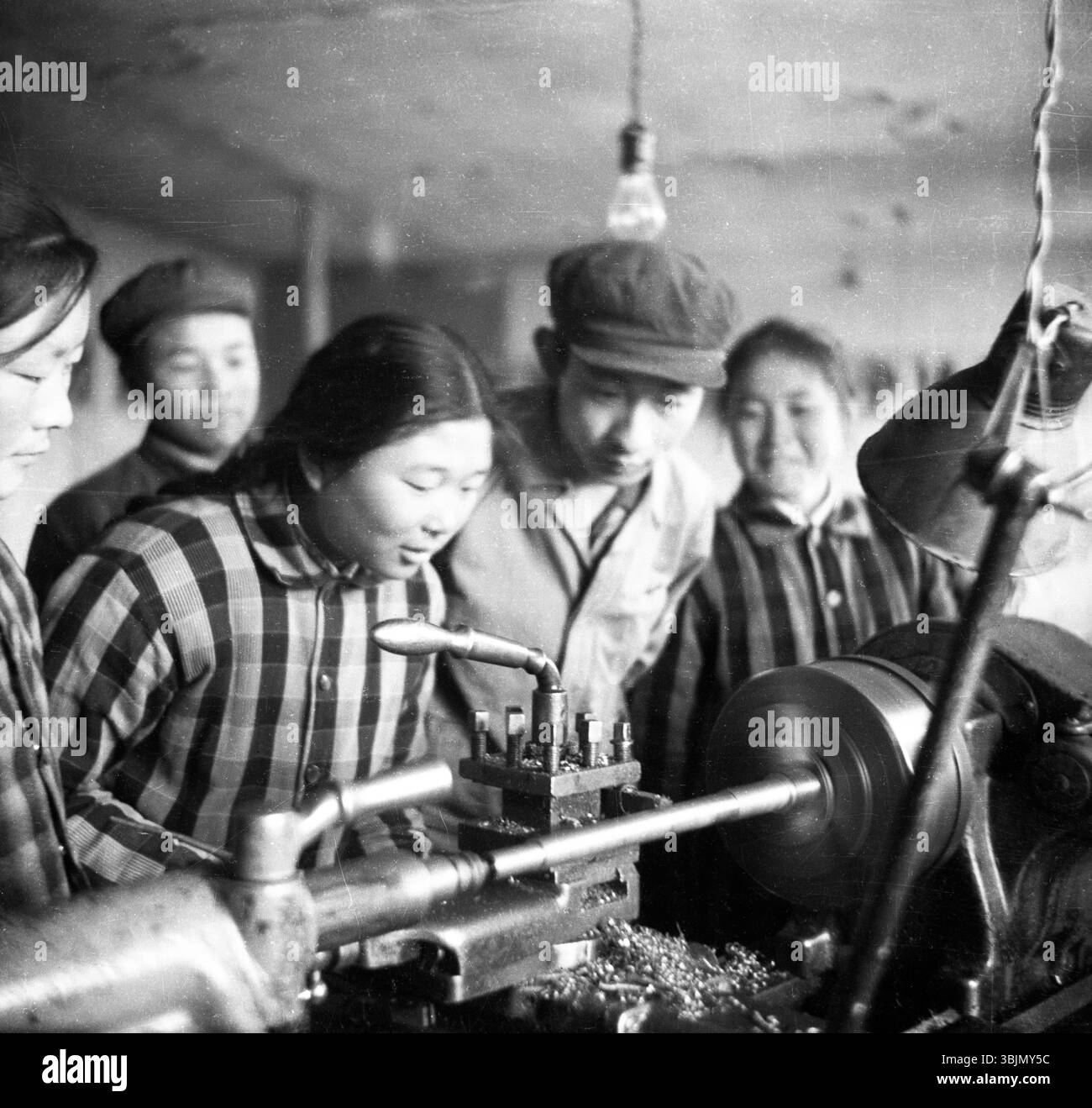 China Factory Workshop der 1970er Jahre – Junge Arbeiter, die Drehmaschinen bedienen Stockfoto