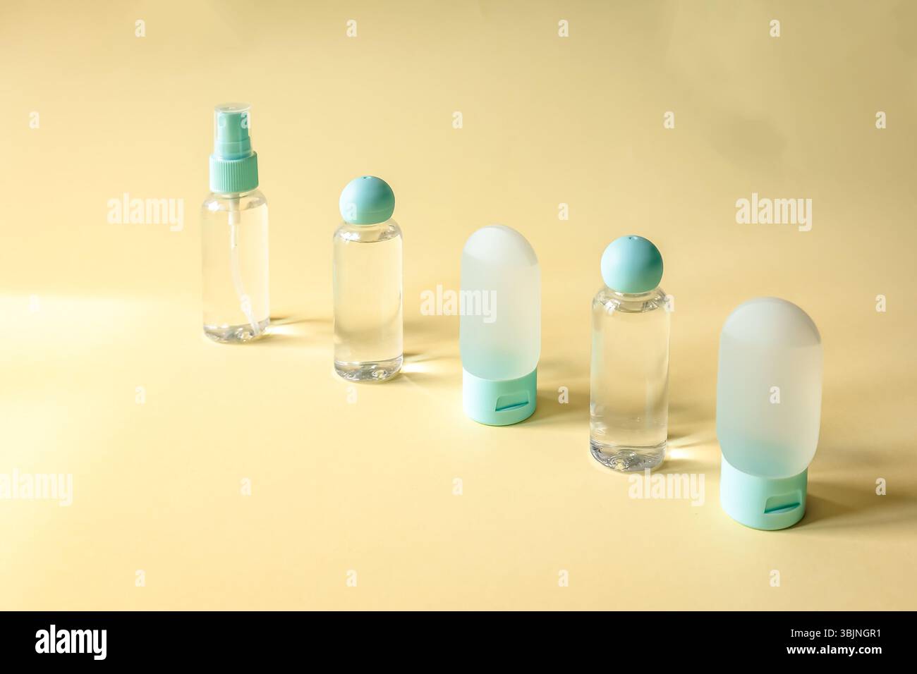 Satz nachfüllbarer Behälter in Reisegröße diagonal auf weichem gelbem Hintergrund angeordnet. Sauber, stilvoll und ideal für Kosmetik, Hygiene oder Urlaub Stockfoto