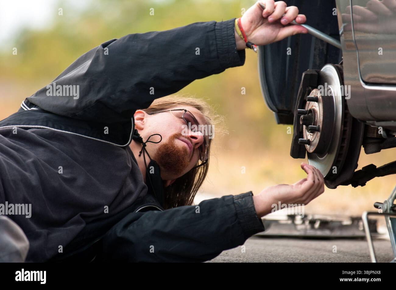 Hübscher junger Mann repariert Platten Reifen Stockfoto