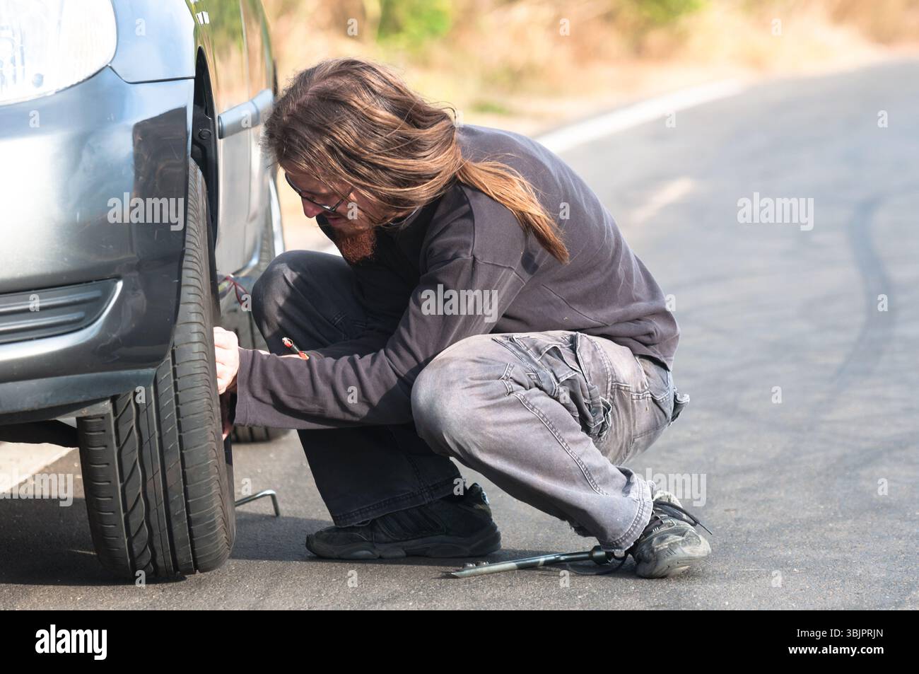 Junger Mann Reparatur Auto im Freien sitzen Stockfoto