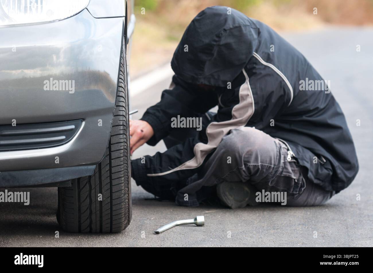 Junger Mann Reparatur Auto im Freien sitzen Stockfoto