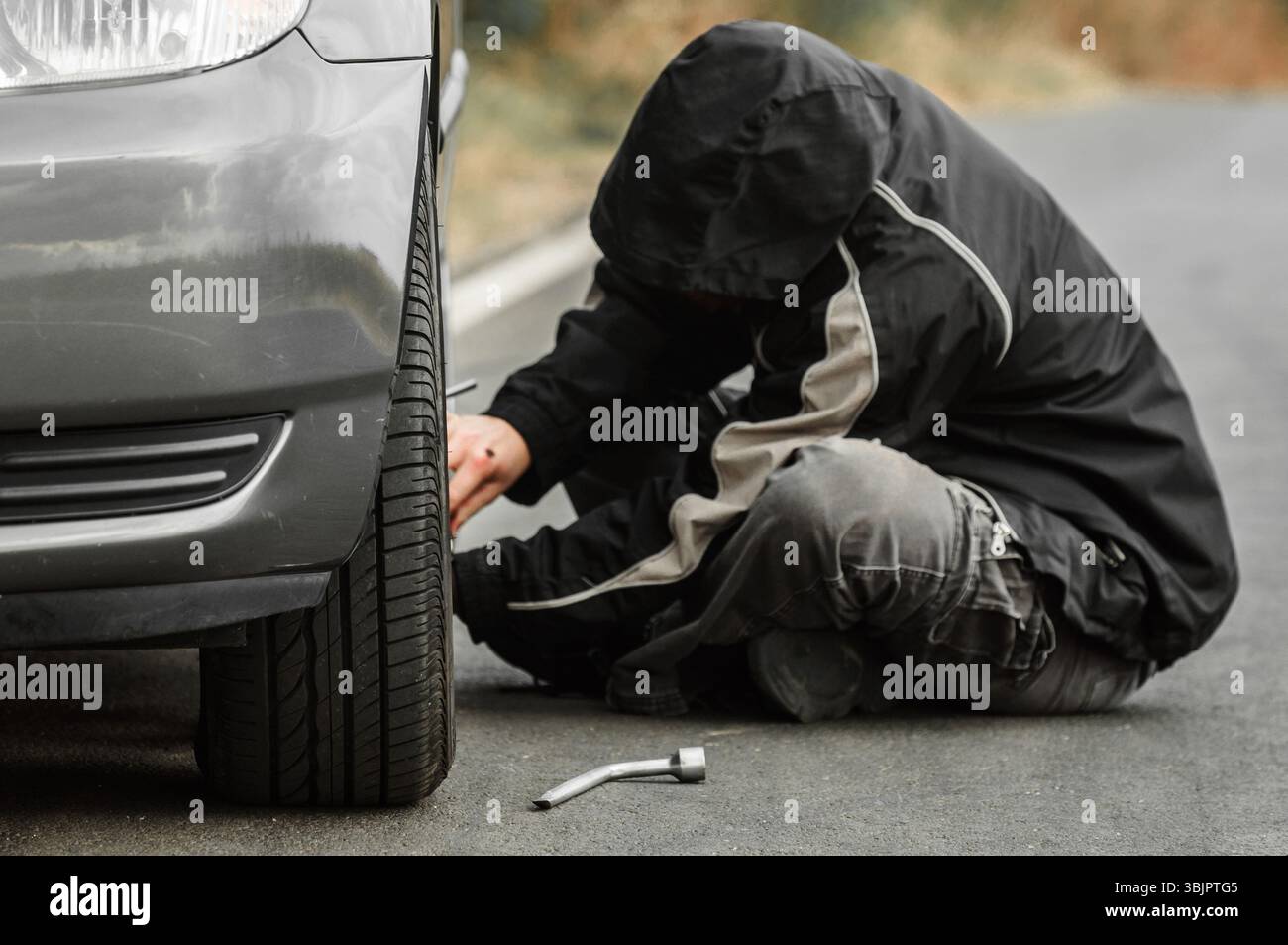 Junger Mann Reparatur Auto im Freien sitzen Stockfoto