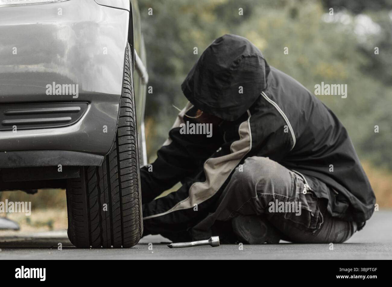 Junger Mann Reparatur Auto im Freien sitzen Stockfoto
