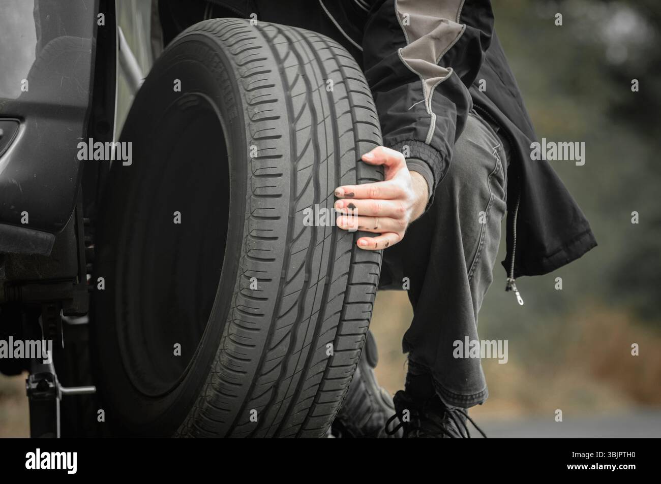 Junger Mann Reparatur Auto im Freien sitzen Stockfoto