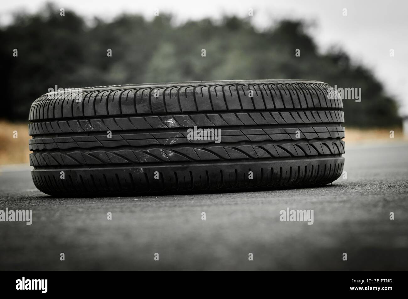 Verlassene Autoreifen auf der Straße mit grünem Hintergrund Stockfoto