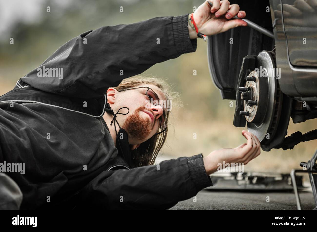 Hübscher junger Mann repariert Platten Reifen Stockfoto