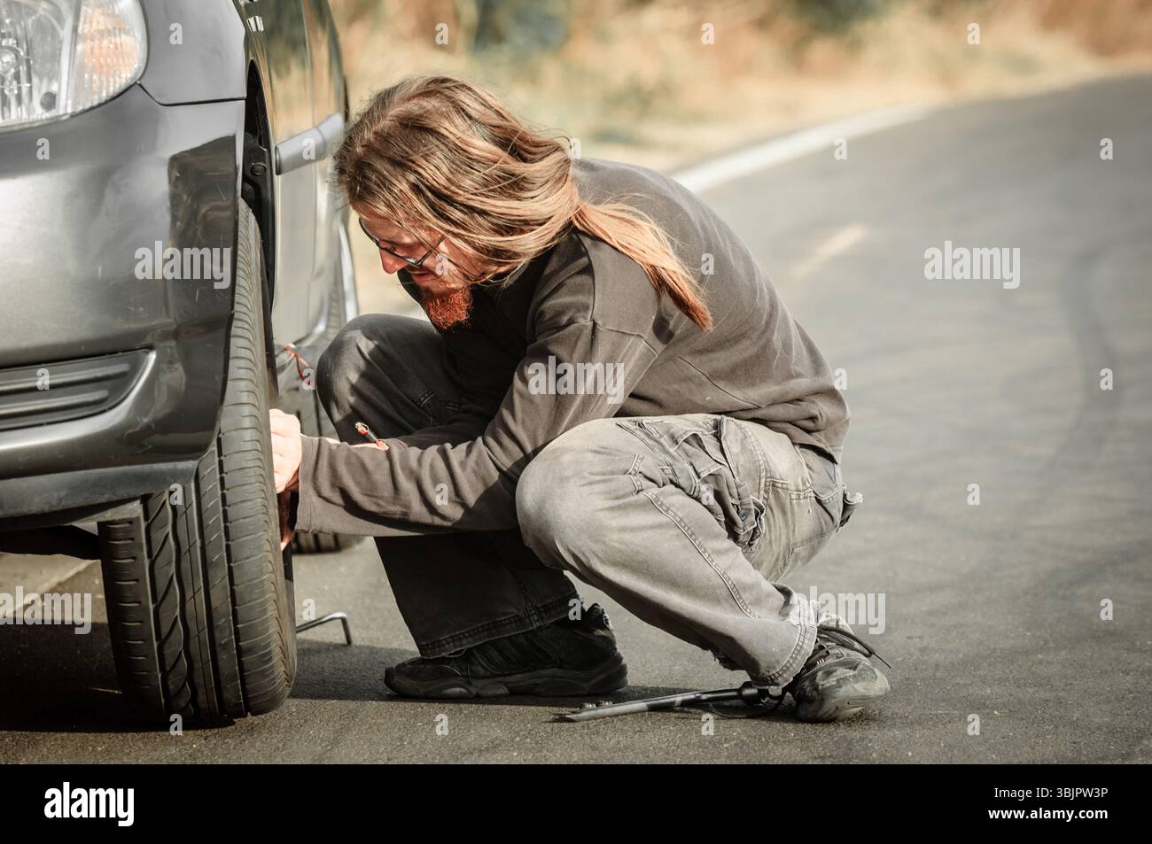 Junger Mann Reparatur Auto im Freien sitzen Stockfoto