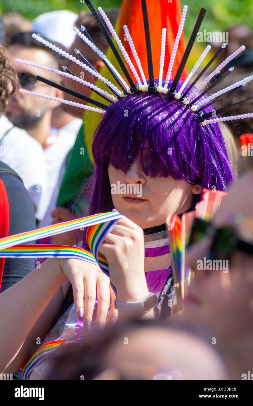 Teilnehmer mit lila Perücke und Regenbogenfan bei der Warschauer Pride Parade in Warschau, Woiwodschaft Masowien, Polen, Juni 2025 Stockfoto