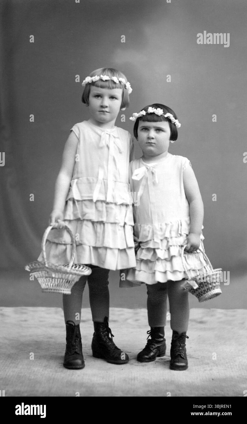 2 Mädchen mit Blumenkränzen, 1910, zwei Mädchen in Kleidern mit Blumenkörben posieren in einem Atelier, historisches Foto Stockfoto