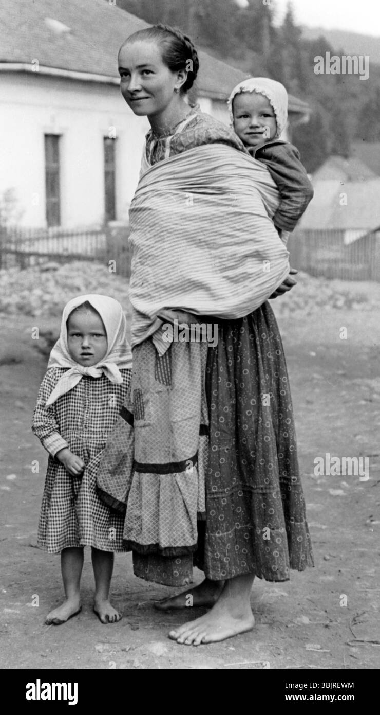 Bauernfrau und Kinder, 1930er Jahre, Eine Frau mit zwei Kindern in traditioneller Kleidung auf einer staubigen Straße, historisches Foto Stockfoto