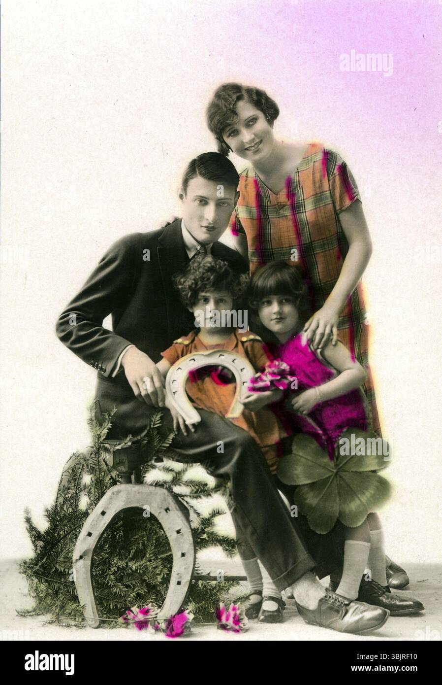 Hufeisen Lucky Family, 1910, Eine Familie posiert zusammen mit Glückssymbolen wie Hufeisen und Kleeblatt, historisches Foto Stockfoto