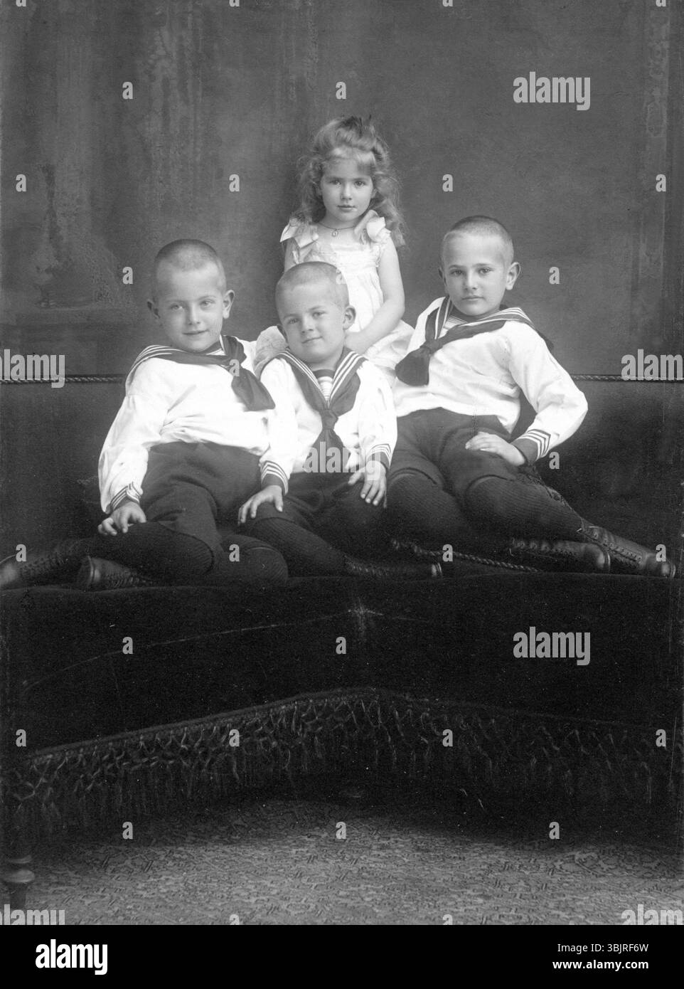 Drei Jungen und ein Mädchen, 1930er, drei Jungen und ein Mädchen in traditioneller Kleidung posieren zusammen auf einem Sofa, Historisches Foto Stockfoto