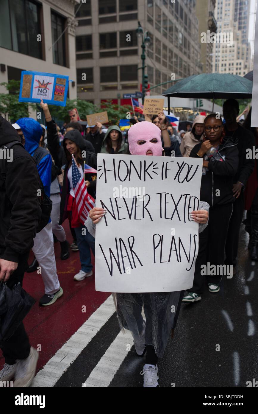 Eine Person, die eine rosafarbene Sturmhaube und einen Poncho aus Plastik trägt, hält ein Schild mit der Aufschrift „Honk if you never texted war Plans“ bei einem Protest im Freien. Anderer Protest Stockfoto