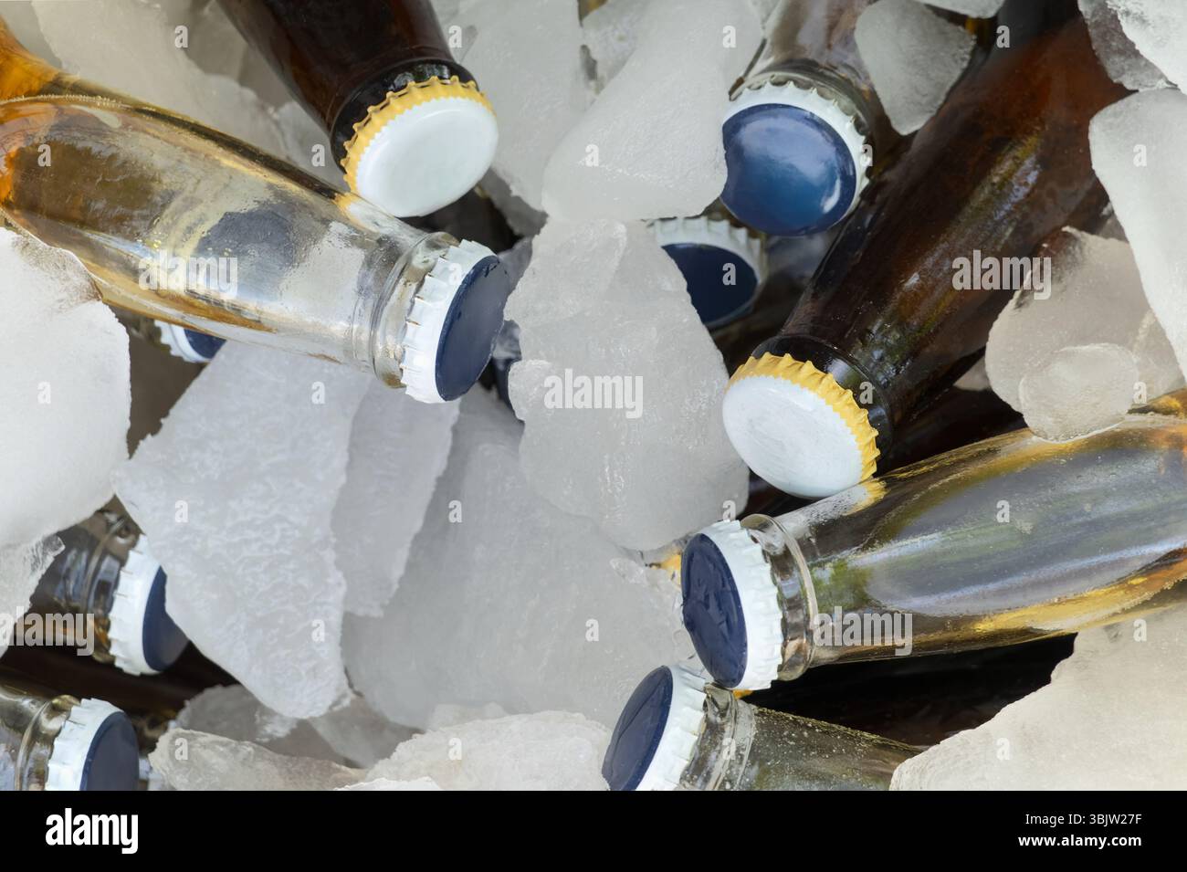 Mehrere mit kalten Getränken gefüllte Flaschen liegen zwischen Eiswürfeln und bieten einen erfrischenden Anblick. Die Szene findet wahrscheinlich während eines Sommertorts statt Stockfoto