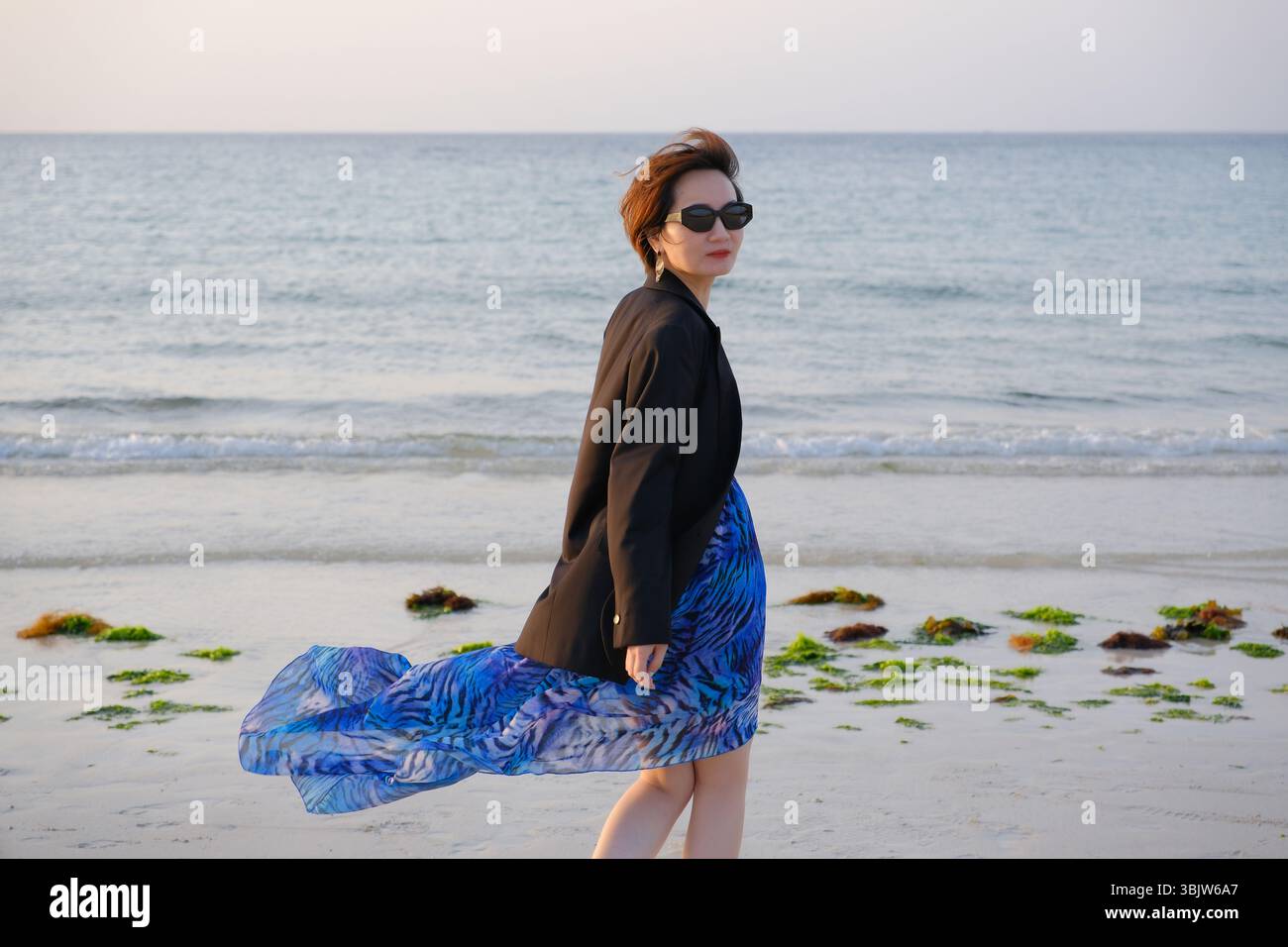 Asiatische Frau, die über die Schulter am Hamdeok Beach schaut. Reisen Sie in Jeju, Südkorea Stockfoto