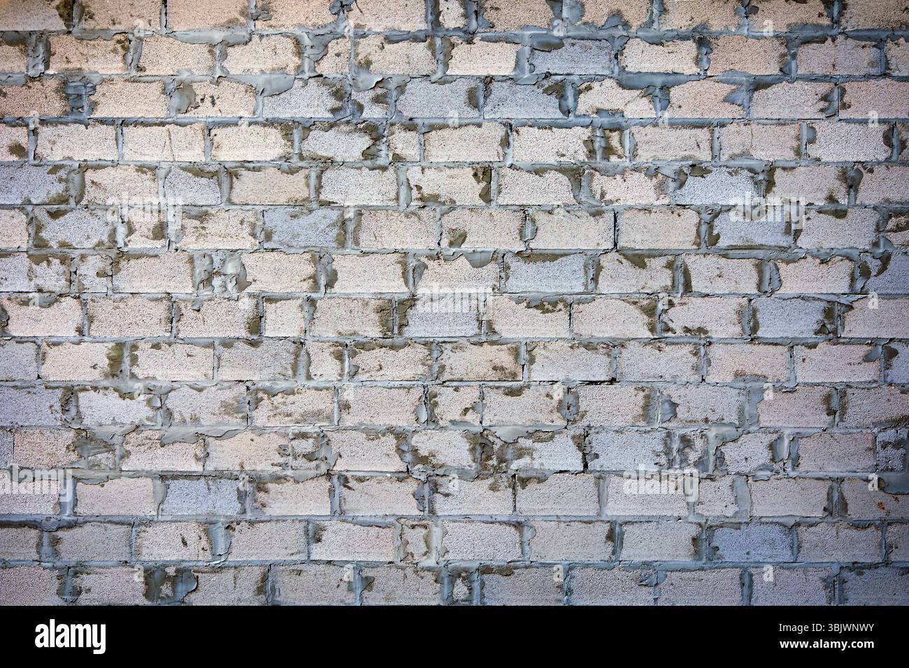 Unvollendete Ziegelmauer mit Mörtel in Bearbeitung. Nahaufnahme einer unvollendeten Ziegelmauer mit sichtbarem Mörtel zwischen den Ziegeln. Ideal für Stockfoto