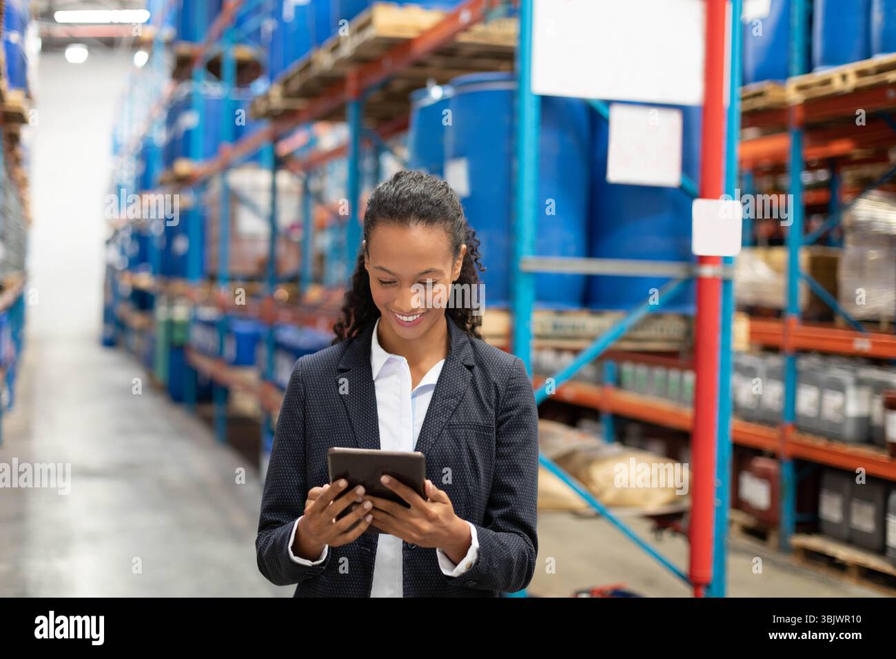 Industrielle Regalanlagen mit blauen Kunststofffässern auf Paletten im Lagergang unter Beleuchtung Stockfoto