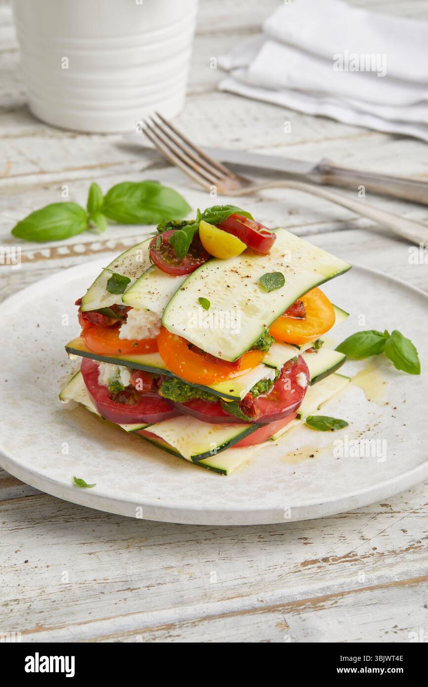 Rohe Zucchini und Lasagne aus Tomaten – ein frisches, ungekochtes Gericht auf Pflanzenbasis mit Kräutern und Gemüse, perfekt als gesundes veganes Mittagessen. Stockfoto