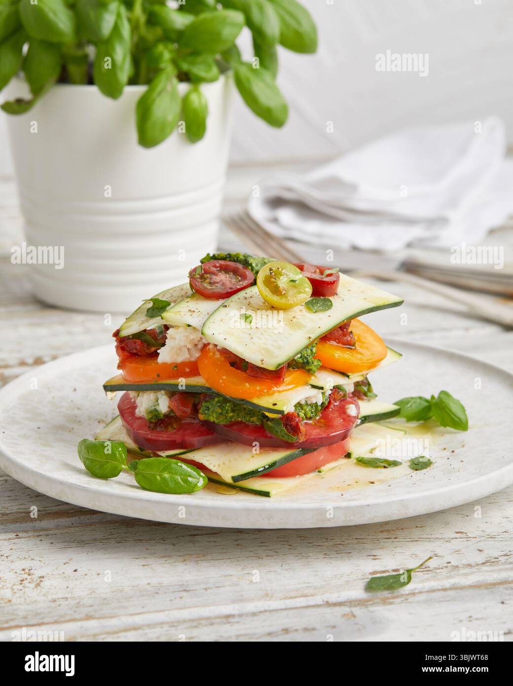 Rohe Zucchini und Lasagne aus Tomaten – ein frisches, ungekochtes Gericht auf Pflanzenbasis mit Kräutern und Gemüse, perfekt als gesundes veganes Mittagessen. Stockfoto