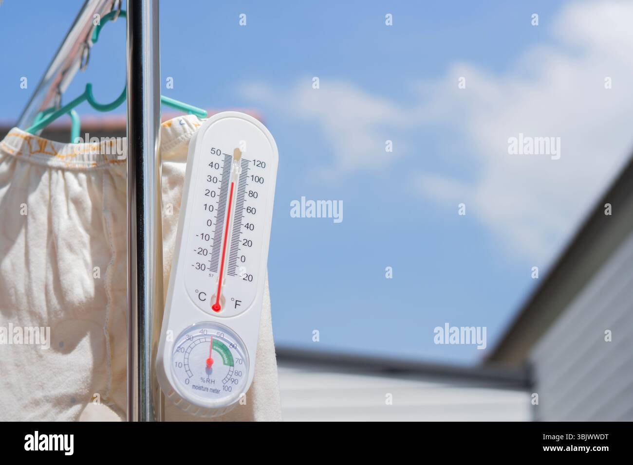 Das Thermometer hängt an sonnigen Tagen über klarem blauem Himmel mit Kopierraum an einem Leinen aus Aluminium. Messkonzept. Stockfoto