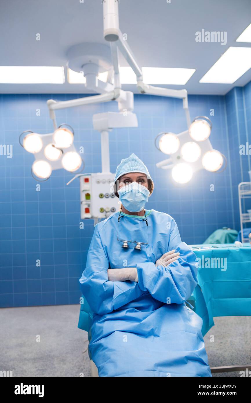 Chirurg, der in ODER mit Deckenleuchten sitzt, die den Instrumententisch mit Werkzeugen beleuchten Stockfoto