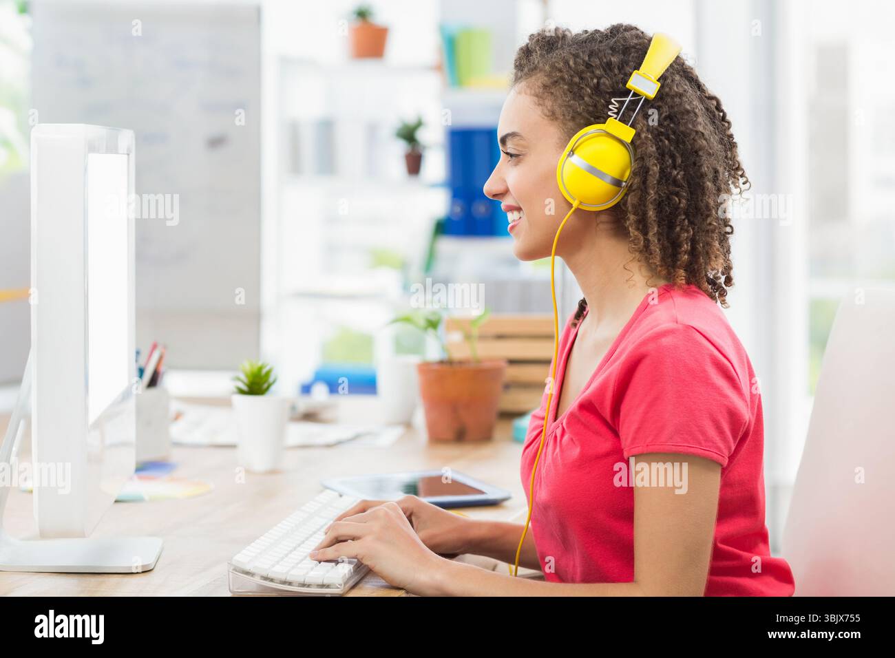 Der Computermonitor sitzt im Home Office auf einem Holzschreibtisch mit weißer Tastatur, Tablet und Stifthalter Stockfoto