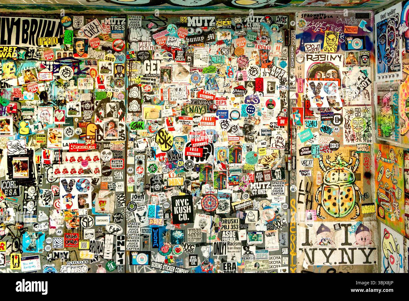 Eine lebendige Wand mit einer eklektischen Mischung aus Stickern und Street Art zeigt urbane Kultur und vielfältige künstlerische Ausdrucksformen in manhattan New york Stockfoto