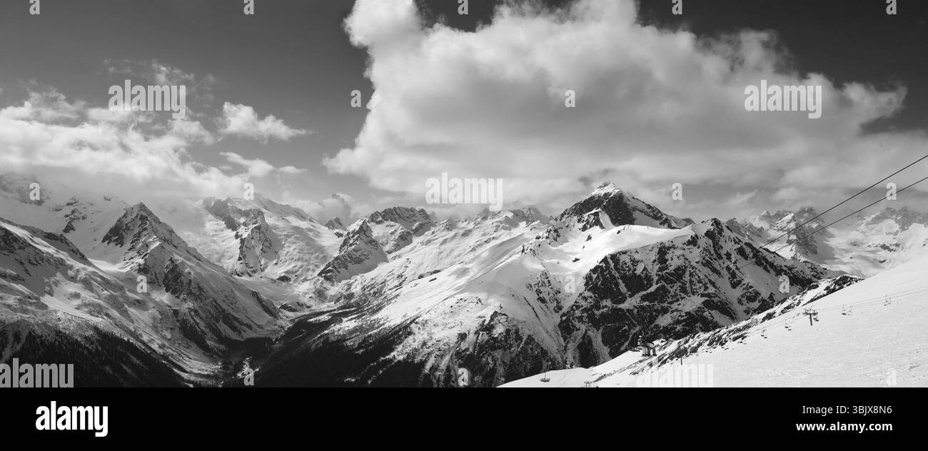Schwarz-weiß-Panorama der Skipiste und bewölkten Berge Stockfoto