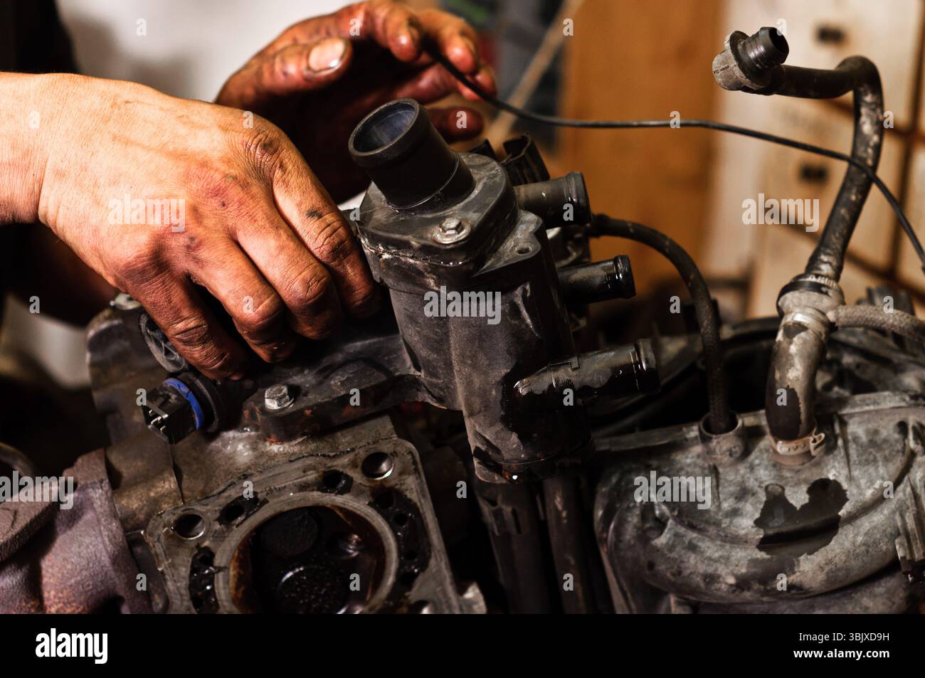 Hände eines Arbeiters, der einen kaputten Motor repariert Stockfoto