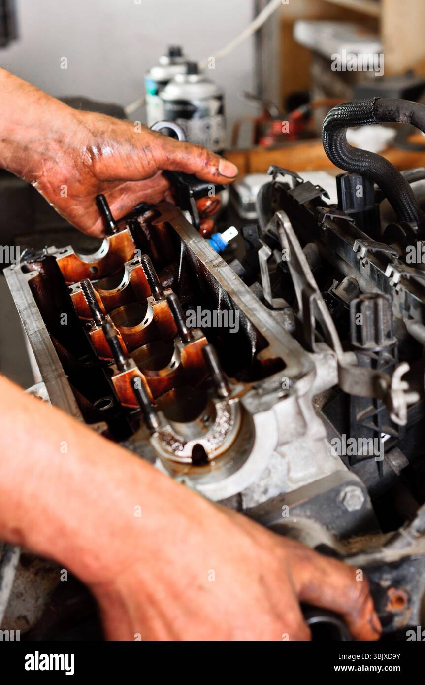Hände eines Arbeiters, der einen kaputten Motor repariert Stockfoto