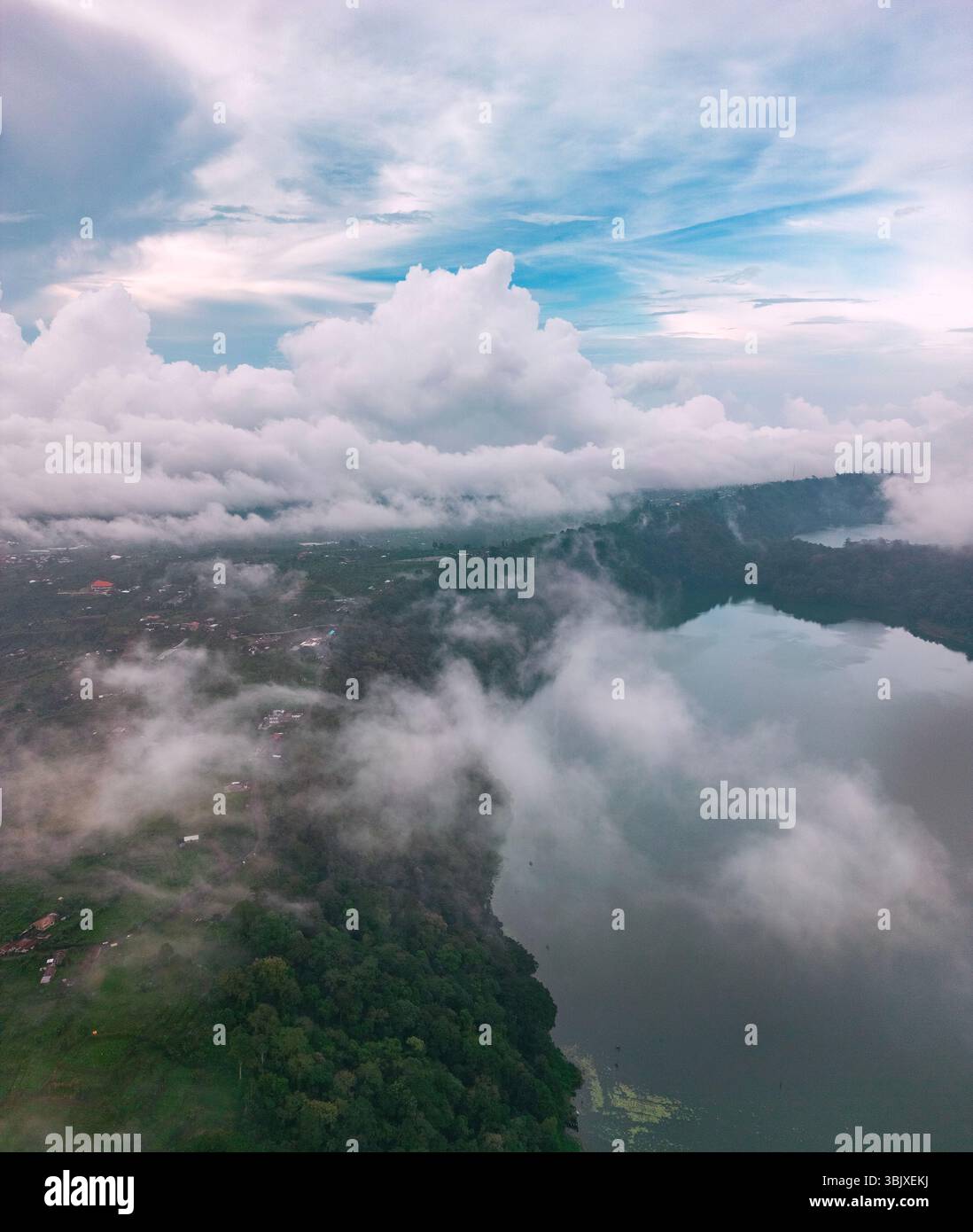 Luftaufnahmen zeigen die ruhige Schönheit Balis mit Wolken, die über dem ruhigen Wasser des Tamblingan-Sees schwimmen. Stockfoto