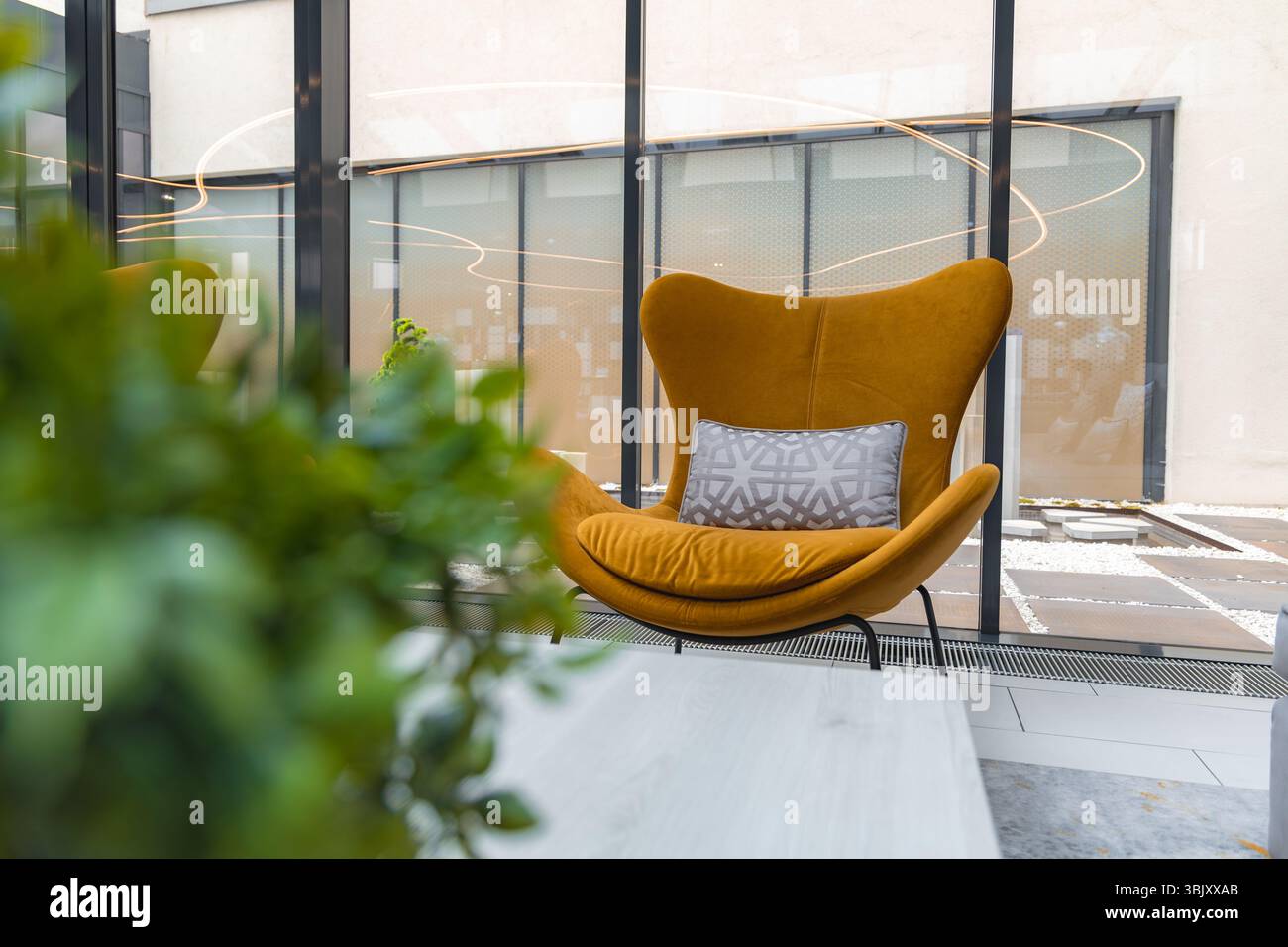 Moderne Inneneinrichtung mit Senfsessel und Blick auf die Glaswand Stockfoto