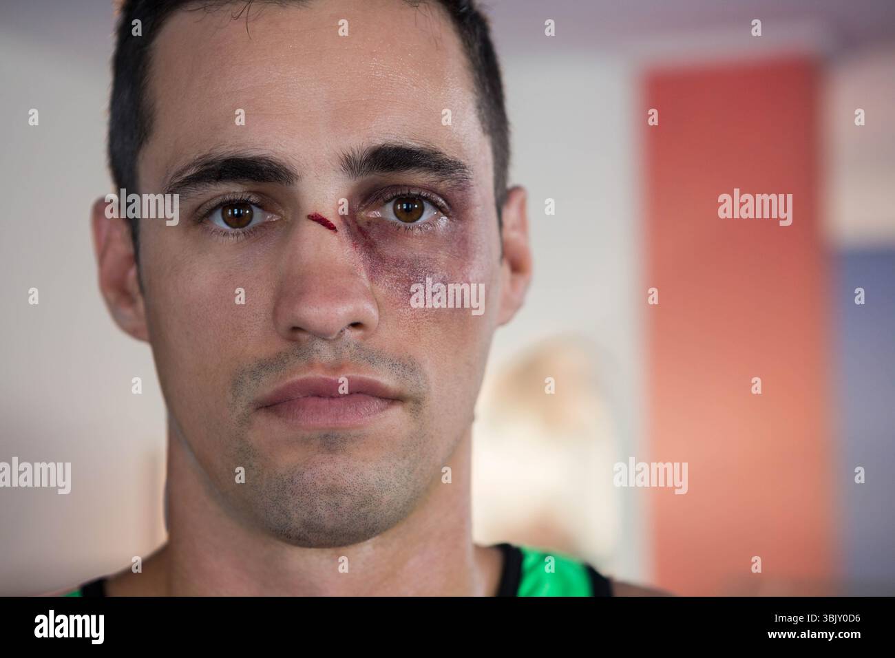 Mann in den frühen 30ern mit grünem Tanktop mit blauen Augen- und Nasenschnitten im Fitnessstudio Stockfoto