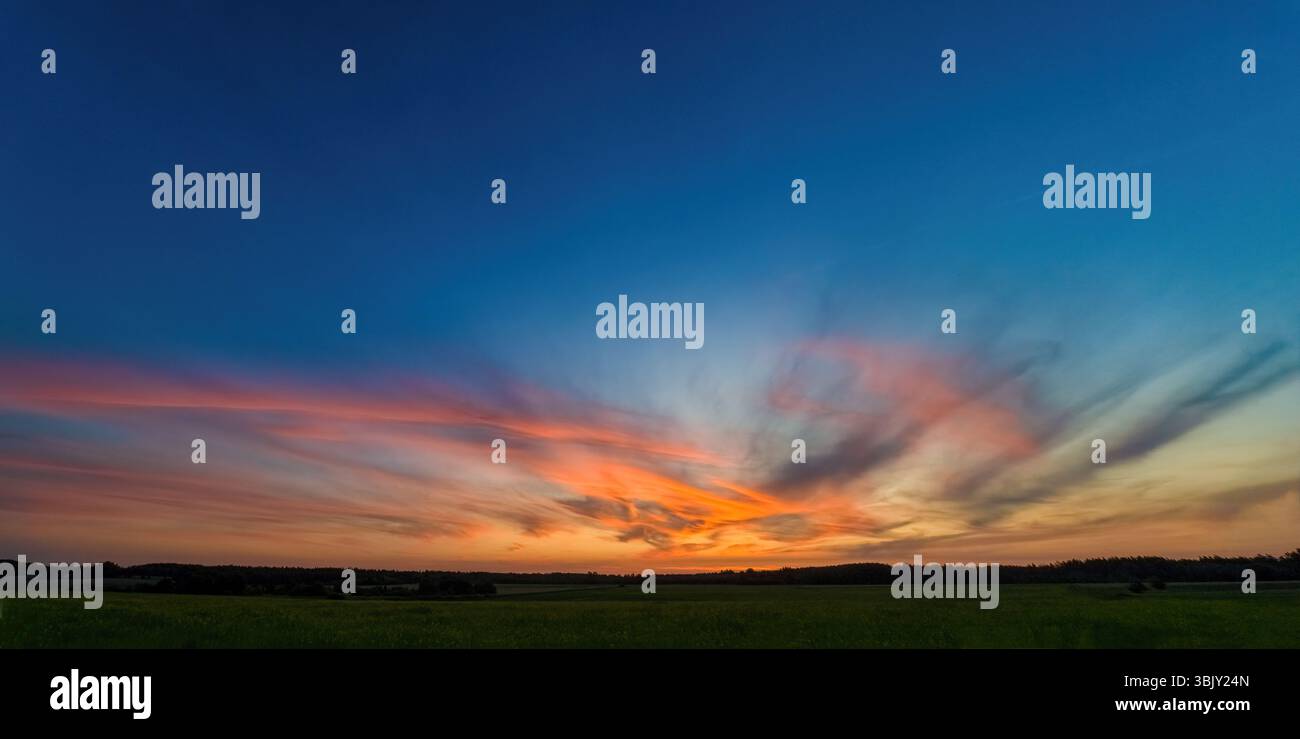 Wunderschöner Himmelhintergrund mit Wolken nach Sonnenuntergang. Roter gelber Himmel. Panorama-Fotografie Stockfoto