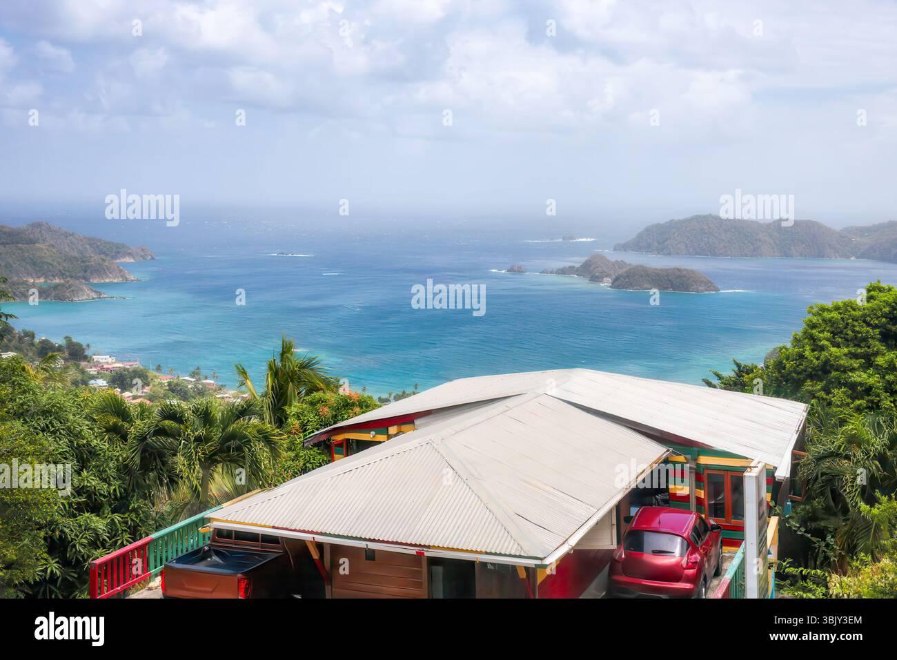 Panoramablick auf ein farbenfrohes Haus am Hügel mit einem Panorama-türkisfarbenen Meer und nahe gelegene Inseln verschwimmen in der Ferne. Tobago Island, Karibisches Meer. Stockfoto