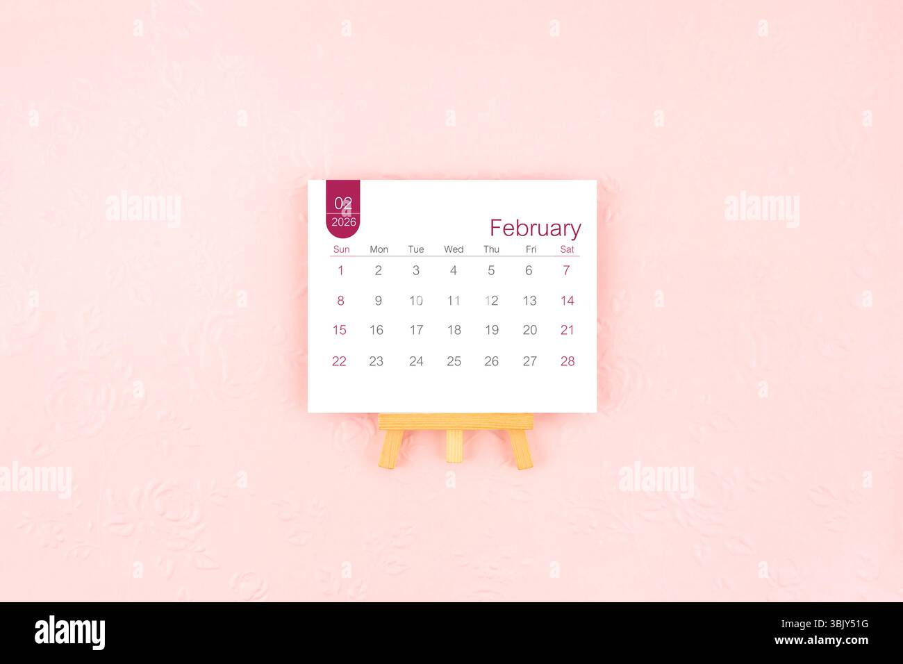 Februar 2026 Kalenderseite mit Holzstaffelei auf rosa Hintergrund. Stockfoto