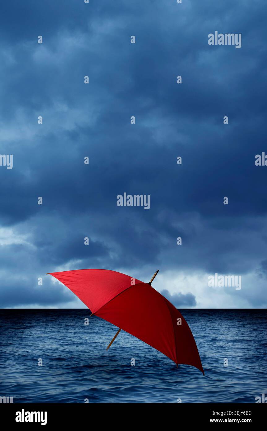 Roter Regenschirm ins Meer mit einem stürmischen Himmel nähert Stockfoto