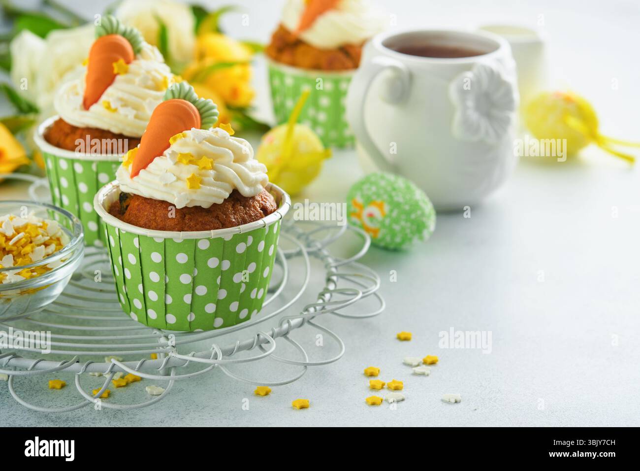 Karottenkuchen Cupcakes zu Ostern. Karotten-Cupcakes mit Frischkäse-Frosting dekoriert mit winzigen MarzipanKarotten auf weißem Backgr Stockfoto