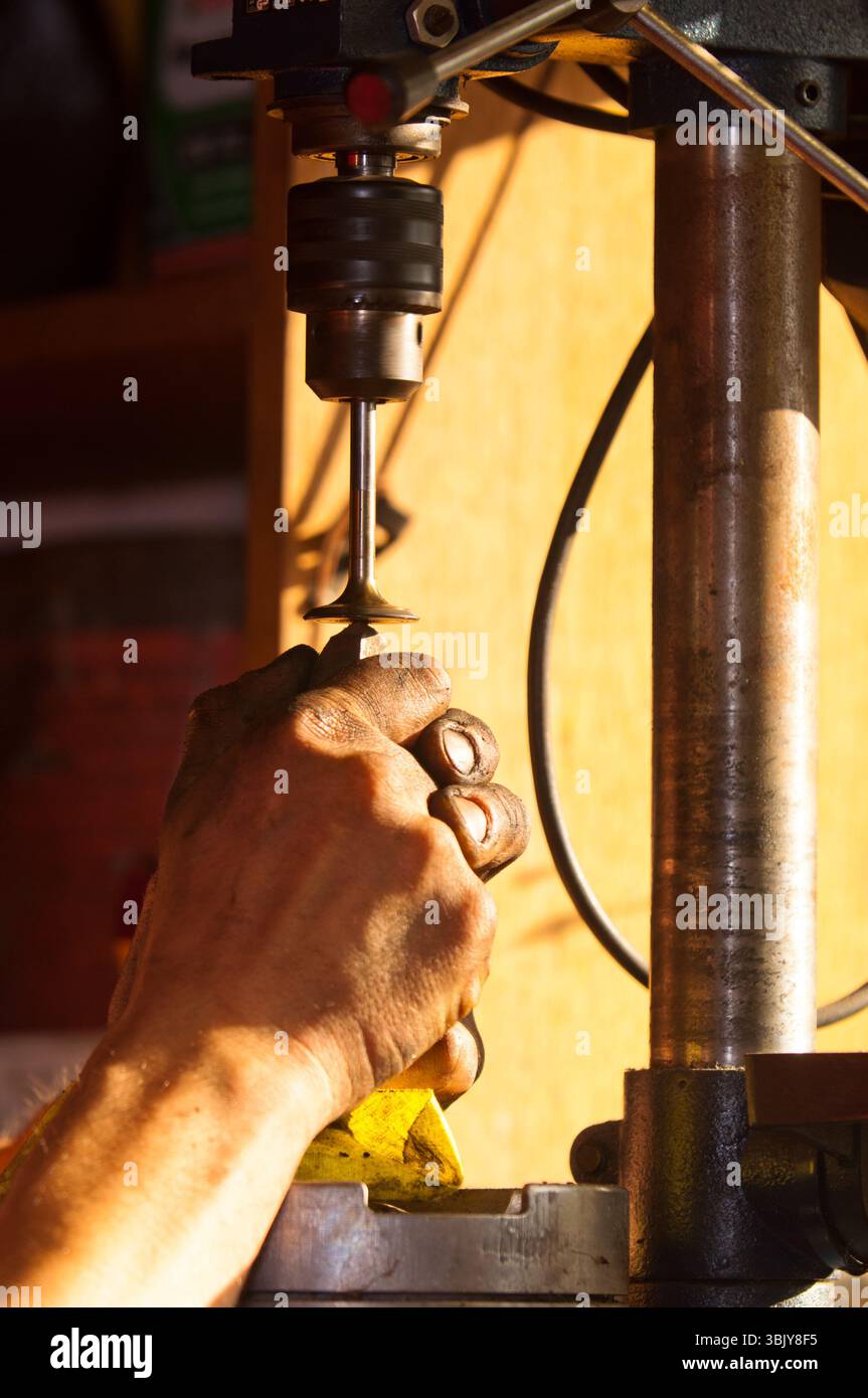 Hände eines Arbeiters, der Motorzylinder poliert Stockfoto