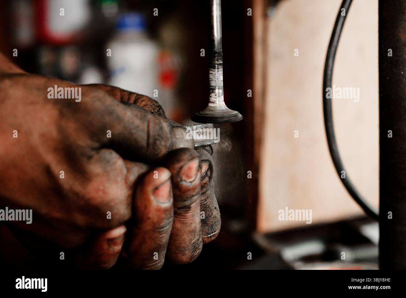 Die Hände des Arbeiters, der die metallische Oberfläche polierend Stockfoto