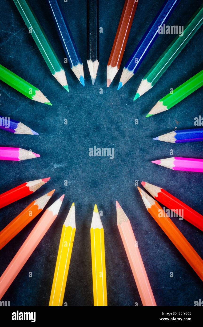 Bunte Bleistifte auf dunklem Hintergrund im Kreis Stockfoto