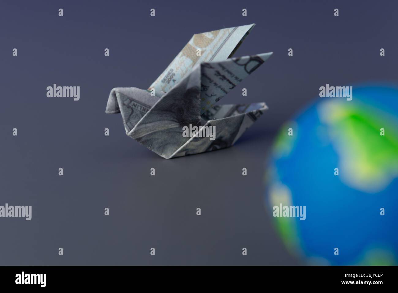 Ein Origami-Vogel, gefaltet von einem US-Dollar-Schein und einem Globus. Globale Finanzen, internationaler Handel und die weltweite Geldbewegung. Stockfoto