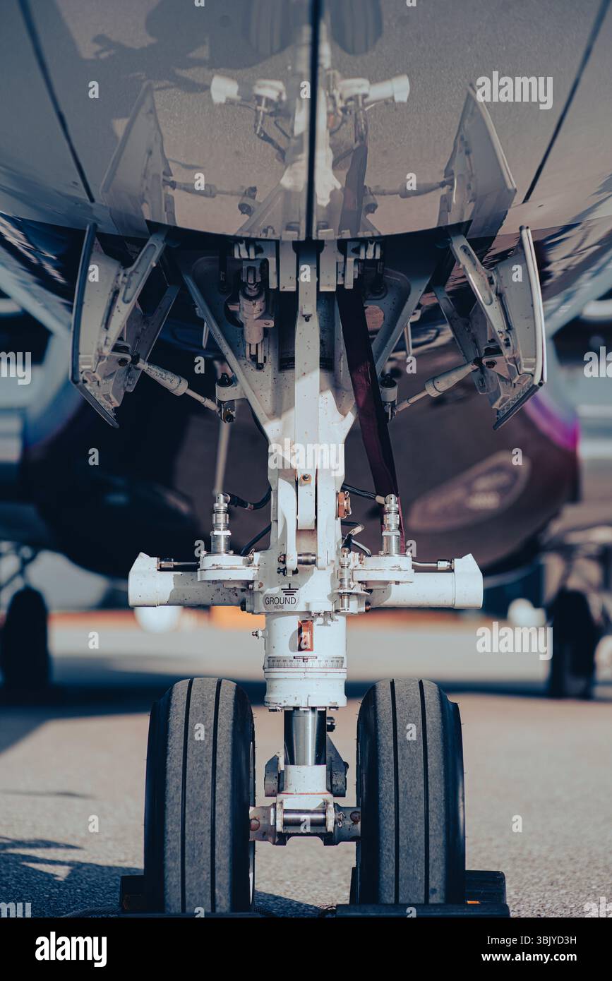 Nahaufnahme des Flugzeugnase-Fahrwerks und der Radbaugruppe mit geöffneten Fahrwerktüren. Schuss vom Boden aus mit detailliertem Flugzeugfahrwerk. Stockfoto
